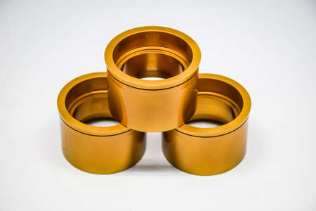 Three large perforated metal cylindrical tubes pierced through dark gold like gold and brass with...