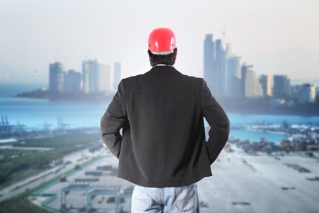 businessman standing  with new modern cranes at the container port terminal with big city backgroundの写真素材