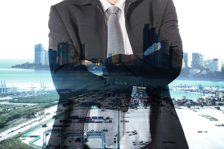 Double exposure of businessman working with new modern cranes at the container port terminal with big city backgroundの写真素材
