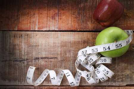 Green apple core and measuring tape. Diet concept with copy space on wood backgroundの写真素材