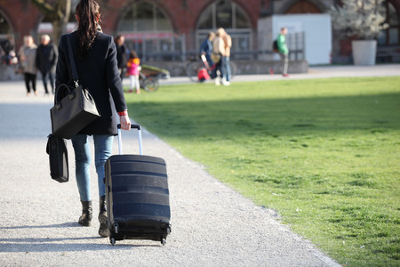 Beautiful woman with suitcases crossing the street in a big city.Beautiful woman  on a street and holding a suitcase. young woman with long legs in a urban settingのeditorial素材