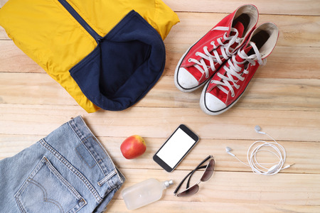 Outfit of traveler, student, teenager, young woman or guy. Overhead of essentials for modern young person. Different objects on wooden background.の写真素材