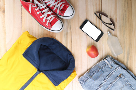 Outfit of traveler, student, teenager, young woman or guy. Overhead of essentials for modern young person. Different objects on wooden background.の写真素材