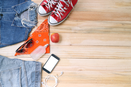 Outfit of traveler, student, teenager, young woman or guy. Overhead of essentials for modern young person. Different objects on wooden background.の写真素材