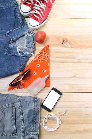 Outfit of traveler, student, teenager, young woman or guy. Overhead of essentials for modern young person. Different objects on wooden background.の写真素材