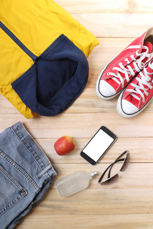 Outfit of traveler, student, teenager, young woman or guy. Overhead of essentials for modern young person. Different objects on wooden background.の写真素材