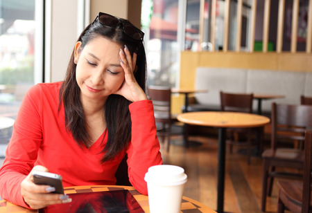 Happy entrepreneur working with a phone and tablet in a coffee shop in the streetの写真素材