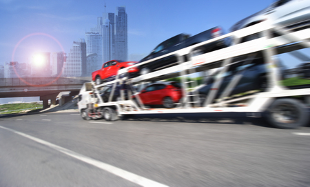 The trailer transports cars on highway with big city background The trailer transports cars on highway with big city background