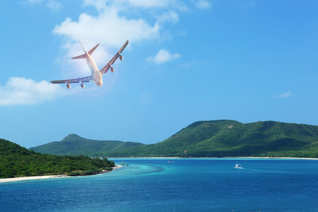 passenger plane flying over beautiful blue ocean and island in purity destination sea beach use for summer holiday vacation travelingの写真素材