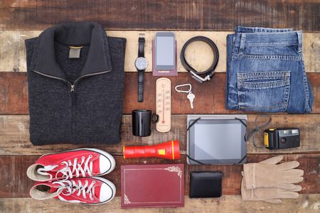 Outfit of traveler, student, teenager, young woman or guy. Overhead of essentials for modern young person. Different objects on wooden background.の写真素材