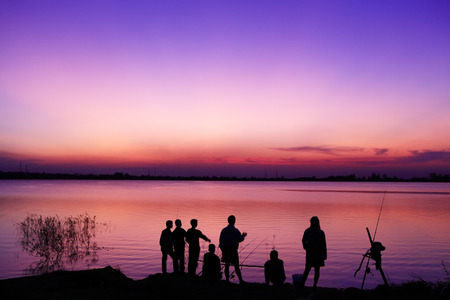 silhouette of group of friends standing in sunsetの写真素材