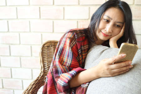 Attractive woman holding a cell phone while looking at the cameraの写真素材