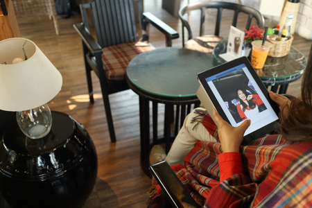 Cafe city lifestyle woman on phone drinking coffee texting text message on smartphone app sitting indoor in trendy urban cafe. Cool young modern mixed race Asian Caucasian female model in her 20s.の写真素材