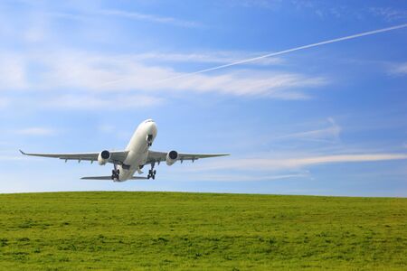 passenger plane flying over beautiful blue sky and green grass use for summer holiday vacation travelingの写真素材