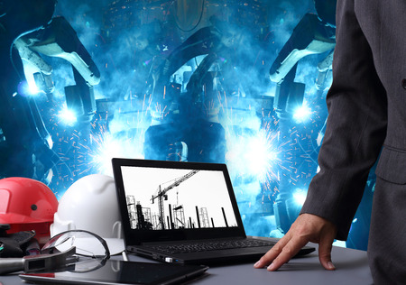 file of safety helmet on table of working engineers with group robot welding automotive industry  business backgroundの写真素材
