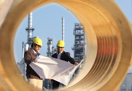 two engineer discussing a new project and through a large cogwheels gear shaft, with large industry...