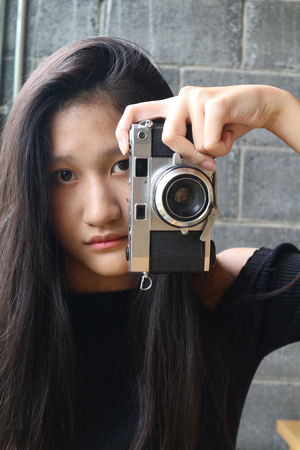 Portrait of fashionable young photographer with vintage film camera, Girl with retro cameraの写真素材