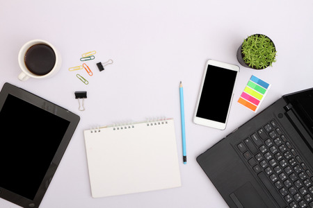 Front view and close up of messy office table with  laptop display, cellphone, coffee cup,...