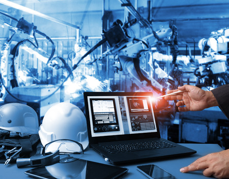 Engineer hand using computer  machine real time monitoring system software.digital manufacturing operation. Automation robot arm machine in smart factory automotive industrial , Industry 4.0 conceptの写真素材