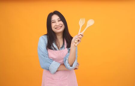 Happy Asian woman is cooking with apron for cooking advertise theme on on yellow background.の写真素材