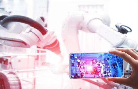 Man hand holding tablet or controller   with automate wireless Robot arm in smart factory...