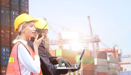 Businesswoman and engineering hold computer or mobile phone working control logistics or import...