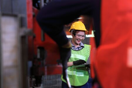 Female Industrial Engineers in Hard Hats Discuss New Project while Using Laptop. They Work in a Heavy Industry Manufacturing Factory.の写真素材