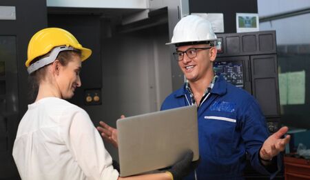 Male and Female Industrial Engineers in Hard Hats Discuss New Project while Using Laptop. They Work...