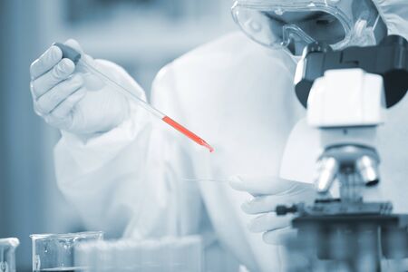 Doctor analyze corona or covid-19 blooding tube, he is finding the sample vaccine in laboratory and he is  wearing ppe suit and mask for protect the virus ,  medical mask, hospital, quarantine outbreak conceptの写真素材