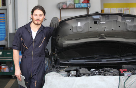 Portrait of a mechanic at work in his garage  or car repair service or auto store, business, maintenance and people conceptの写真素材