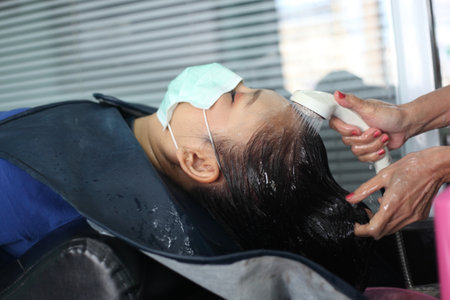 woman customer in a salon with medical masks during virus pandemic. Working with safety mask.の写真素材