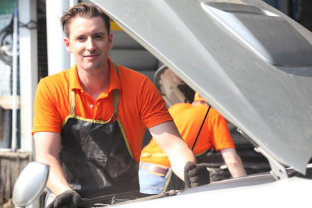 Portrait of a mechanic at work in his garage or car repair service or auto store, business, maintenance and people conceptの写真素材