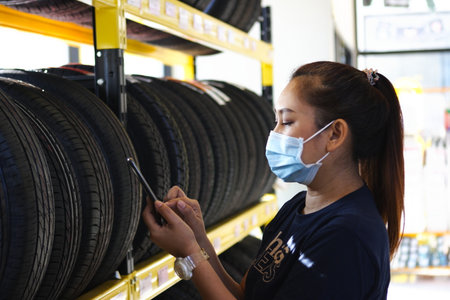 Salesman with showing wheel tires at car repair service or auto store, business, maintenance and people conceptの写真素材