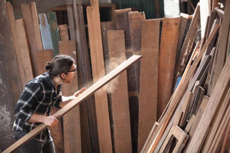 Carpenter, joiner is working in the workshop. Man at work on wood.Image of mature carpenter in the workshop,furniture making concept.の写真素材