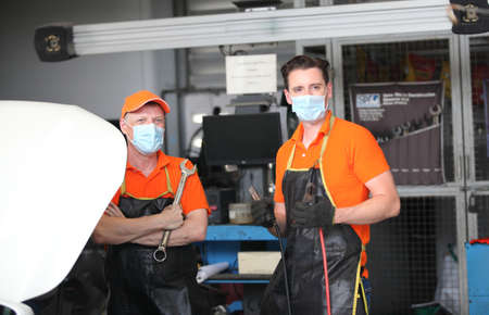 two car mechanic on protective mask anti coronavirus or covid19 ,  they are fixing  and service...