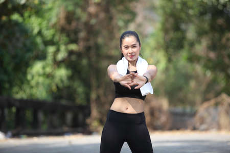 Fitness runner body closeup doing warm-up routine before running, stretching arm muscles with...