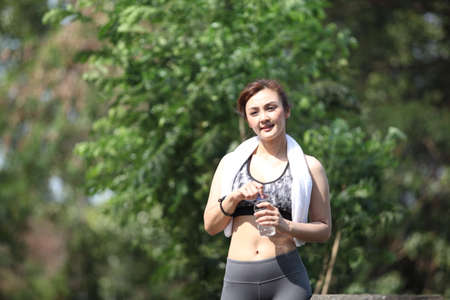 Fitness beautiful woman drinking water and sweating after exercising on summer hot day in beach....