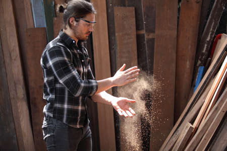 Carpenter, he is working in the workshop. Man at work on wood. Image of mature carpenter in the workshop, furniture making concept.の写真素材