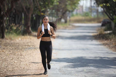 runner - woman running outdoors training for marathon run. Beautiful fit asian fitness model Sporty...