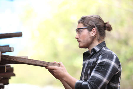 Carpenter, he is working in the workshop. Man at work on wood. Image of mature carpenter in the workshop, furniture making concept.の写真素材