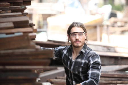 Carpenter, he is working in the workshop. Man at work on wood. Image of mature carpenter in the workshop, furniture making concept.の写真素材