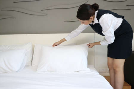 A Young hotel maid making the bed with clean fresh towels