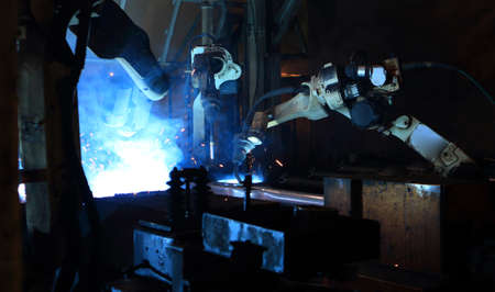 Robot arm in smart factory background. Mixed media of welding robot in the automotive parts industry