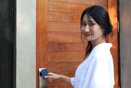 woman  open door with keycard , Closeup of female housekeeper's hands holding cardkey and opening door of hotel roomの写真素材