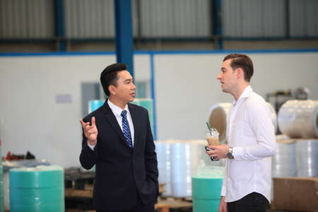 Happy business people talking on meeting at factory industry or Mature company manager greeting a worker  in industrial facility or warehouseの写真素材