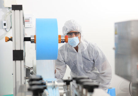 Production engineer with face mask working in factory , Qc engineer checking mask for good quality