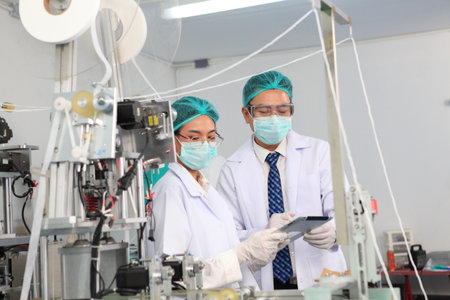 Production engineer with face mask working in factory , Qc engineer checking mask for good qualityの写真素材