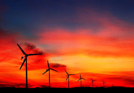 Eco power. Wind turbines generating electricity. Silhouette of the wind turbine at sunrise or sunset...