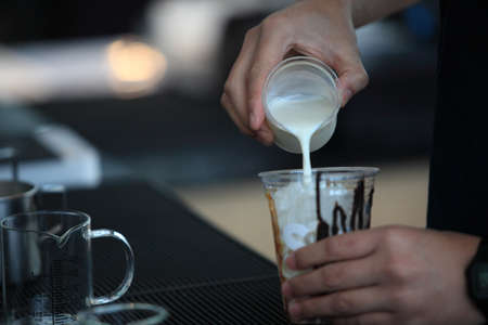 preparing fresh coffee of male hands pouring milk and preparing fresh cappuccino, coffee artist and...