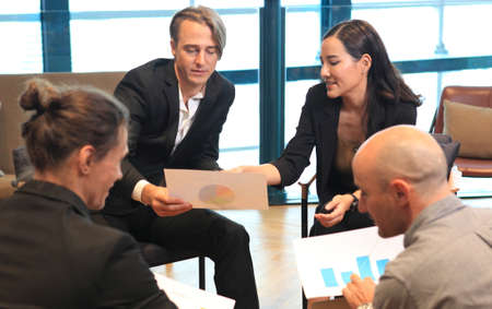 Group of young business people working and communicating while sitting at the office desk together with colleagues sitting in the background. Modern Office Meeting Room Managers and Investors Talkingの写真素材